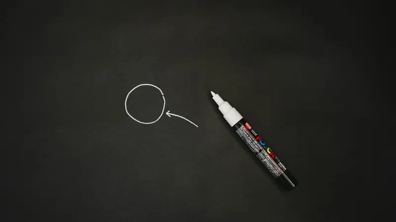 Schwarzer Marker neben einem gezeichneten Kreis auf dunklem Hintergrund