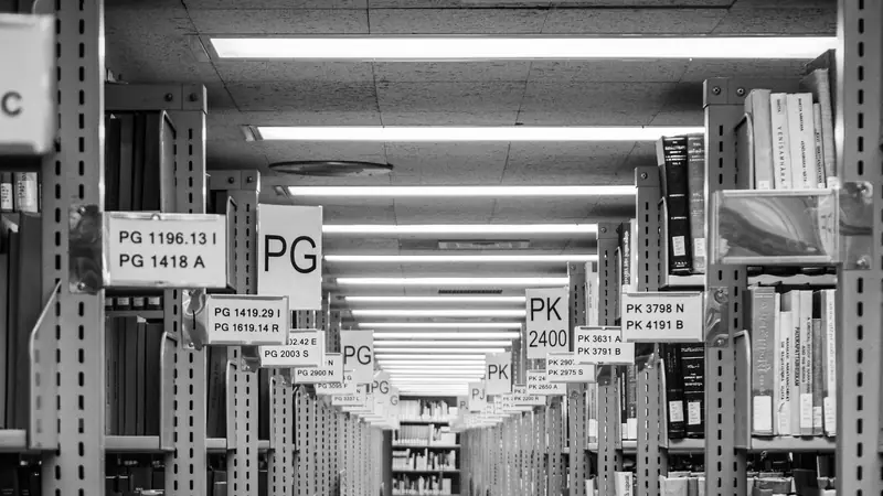Gang zwischen Bibliotheksregalen mit Signaturschildern